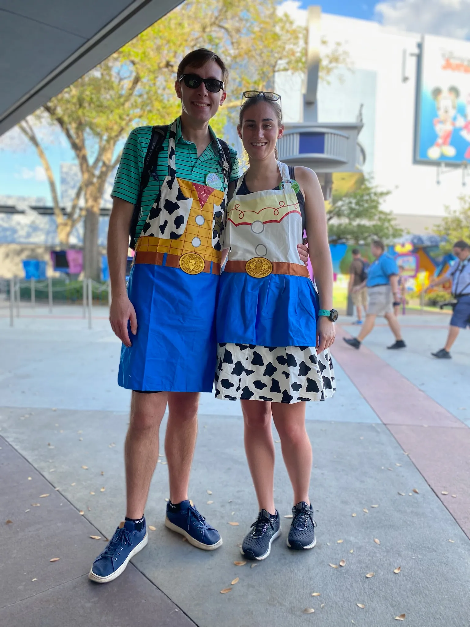 Danielle and Quentin in Disney world wearing Woody and Jessie aprons.