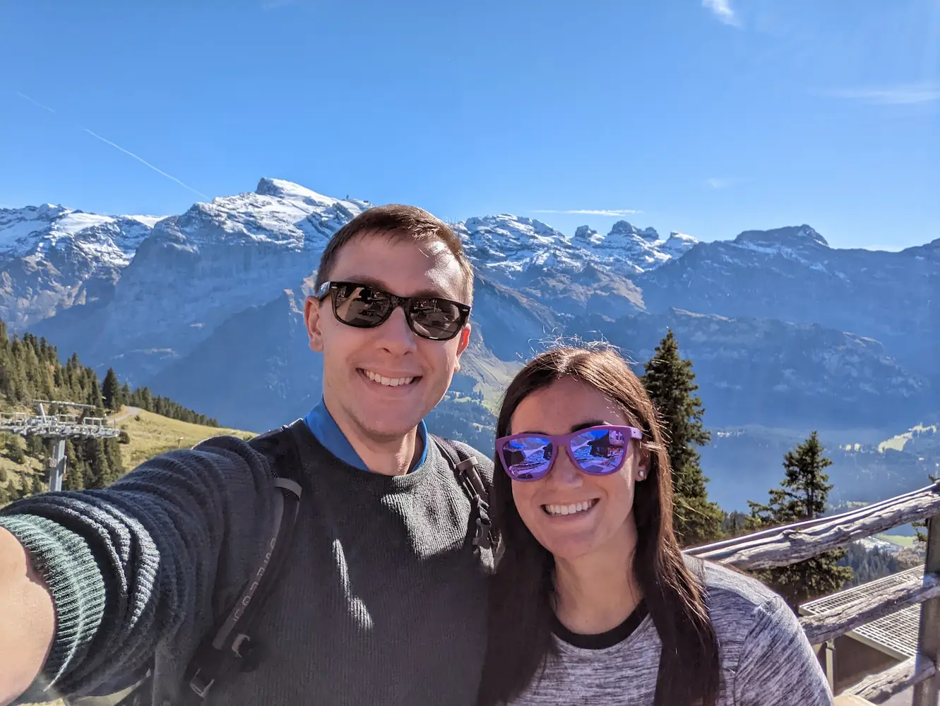 Danielle and Quentin on Mount Brunni in Switzerland, with snowy mountains behind them.