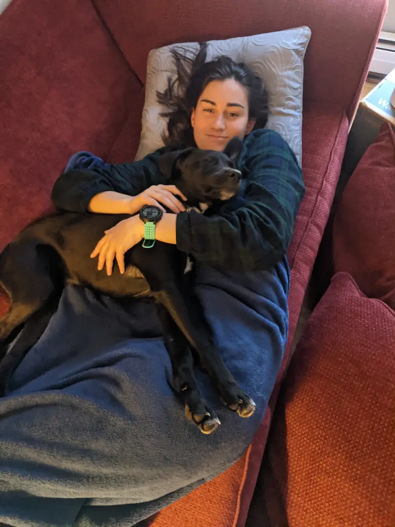 Danielle laying on the couch with Gracie looking very happy.