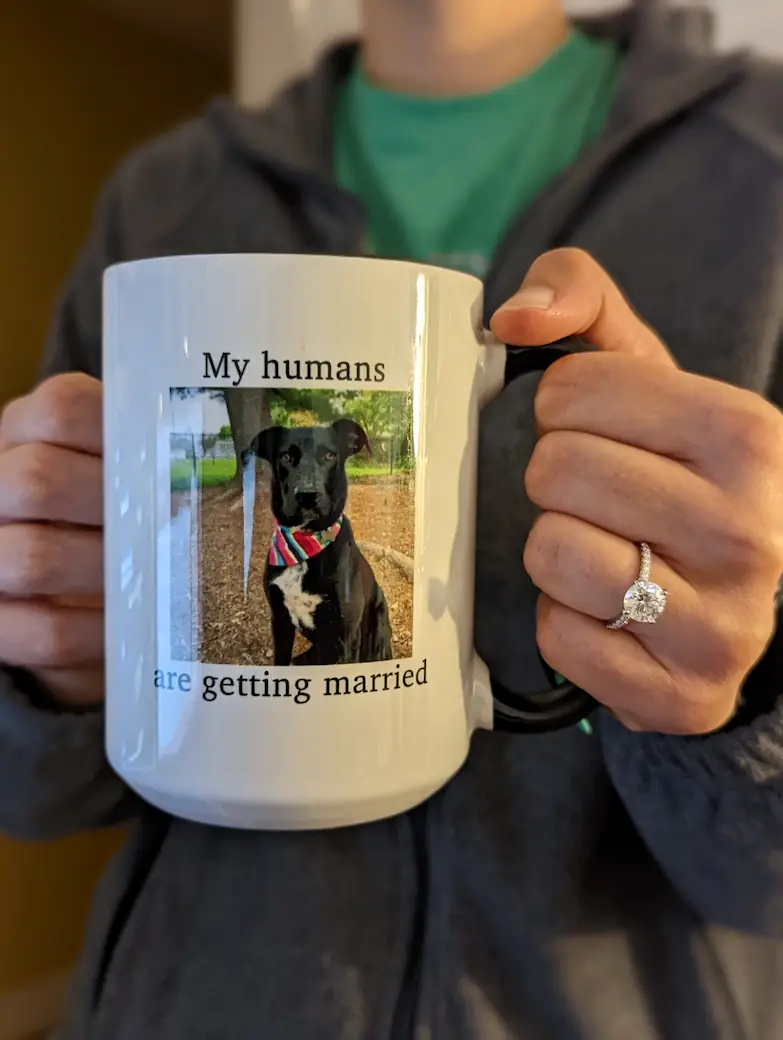 Danielle holding a mug with a picture of Gracie on it, which says 'My humans are getting married'.