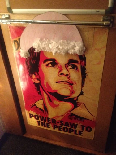 Quentin's Dexter poster with the caption 'Power-saw to the people' with a paper santa hat Danielle made.