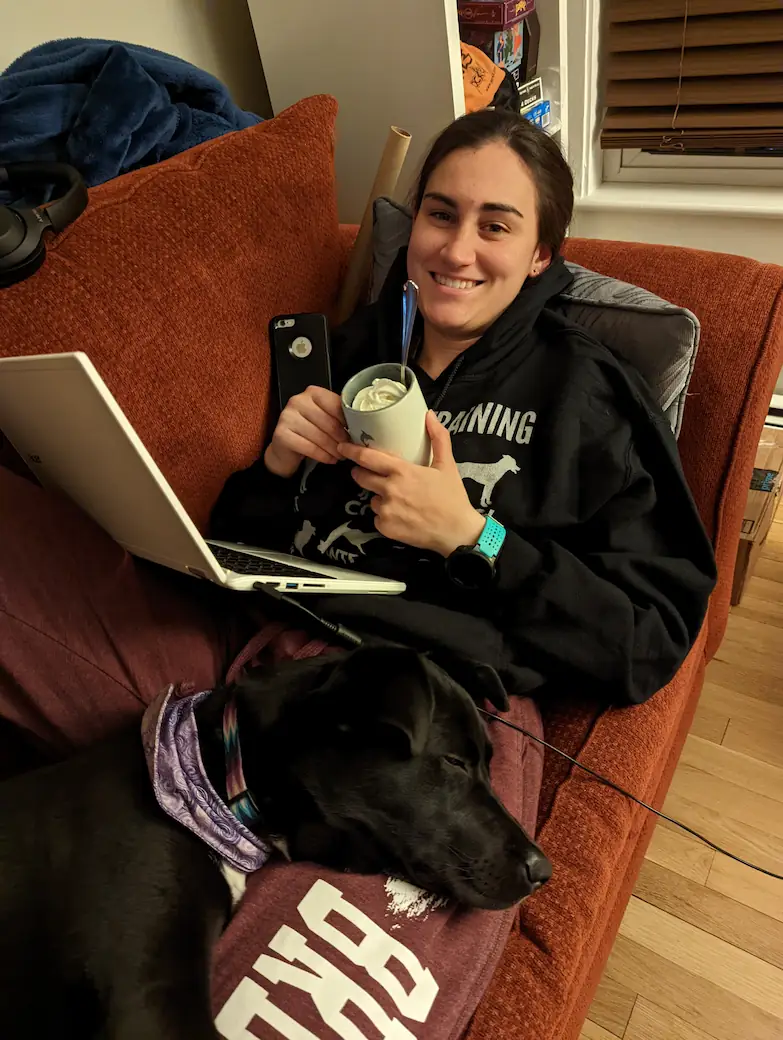 Danielle laying on the couch with ice cream in her hand and Gracie sleeping on her lap.