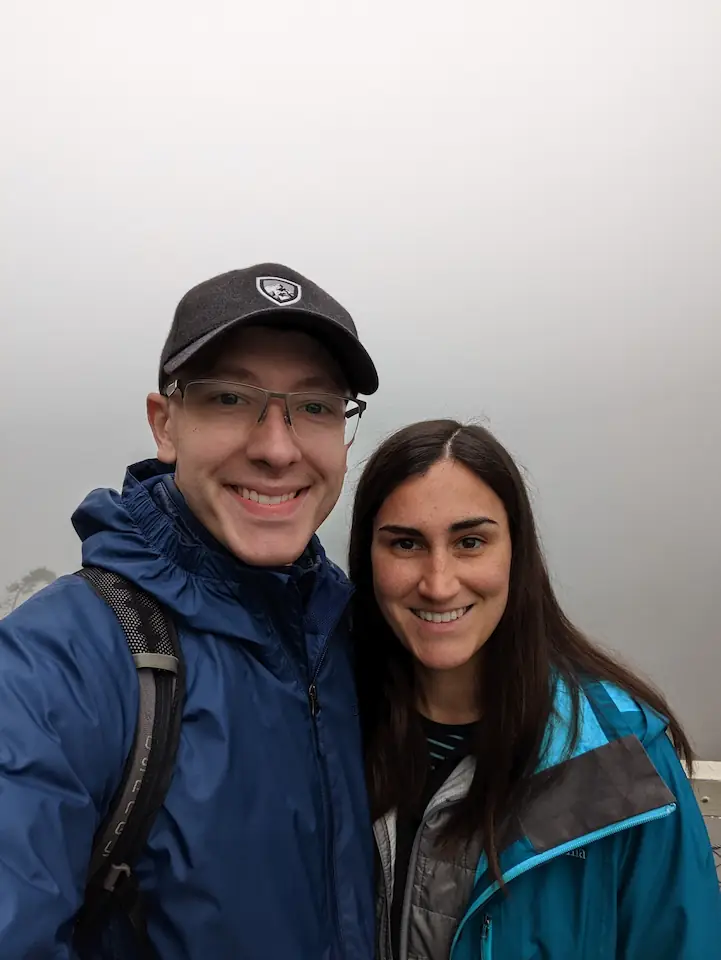 Danielle and Quentin standing on an extremely foggy bridge in front of Neuschwanstein Castle.