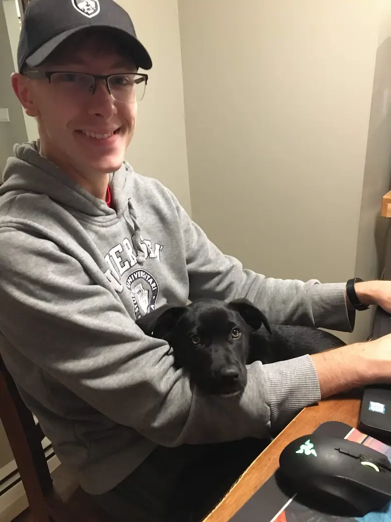 Quentin working at the kitchen table while puppy Gracie is laying in his lap.