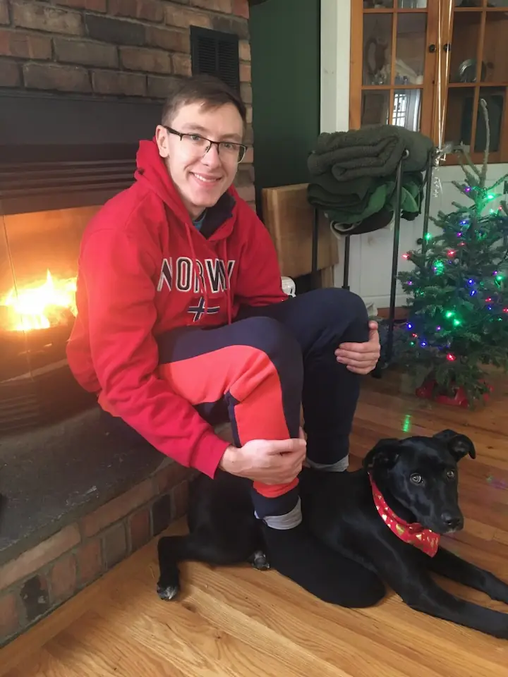 Quentin and Gracie sitting in front of the fire together, Gracie laying between Quentin's feet.